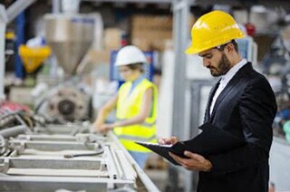 A worker supervising the readings of the machines on the floor of a manufacturing facility