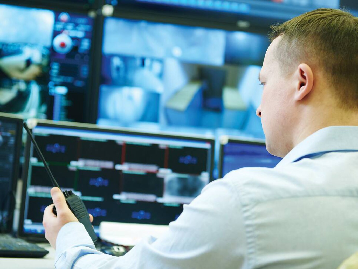 A person holding a walkie talkie in his hand monitors the security cameras