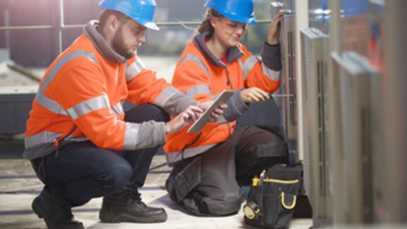 Two construction workers with one looking at the tab while other one fixing with the tool