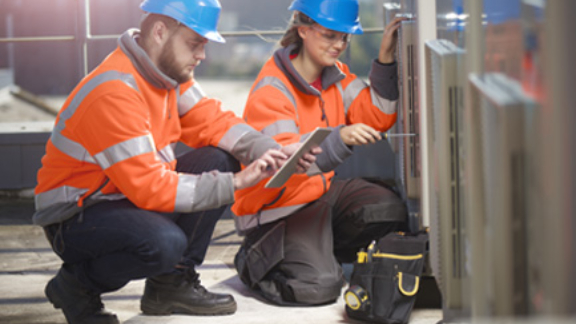 Two construction workers with one looking at the tab while other one fixing with the tool
