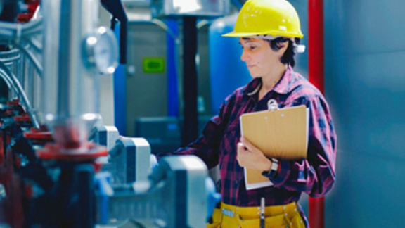 A worker supervising the readings of the machines on the floor of a manufacturing facility
